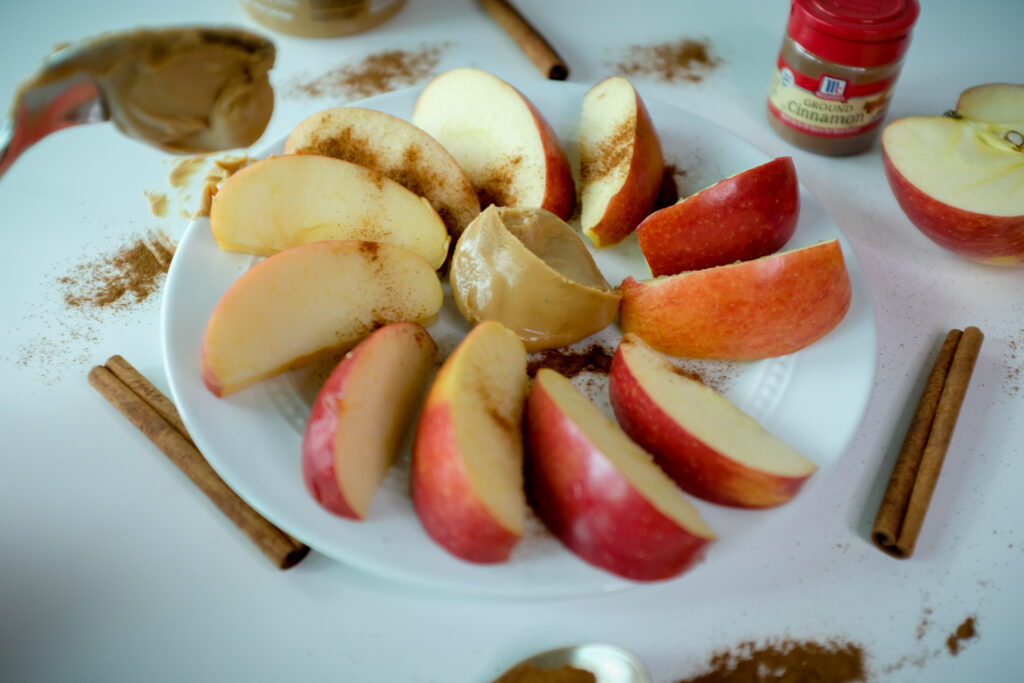 This is an image of apples. nut butter. and ground cinnamon. it is a great healthy snack idea. 